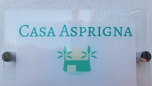 A sign with the text "Casa Asprigna" and a graphic of a house with plants.