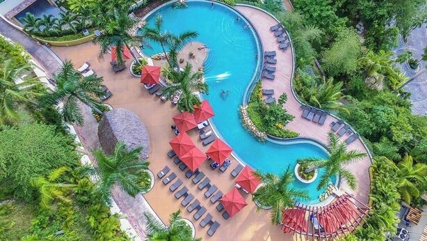 An aerial view of a resort with a large swimming pool, sun loungers, and palm trees. - Garza Blanca, 2 Bdr Panoramic View Hotel Suite in Puerto Vallarta with kitchen. (Jal.)
