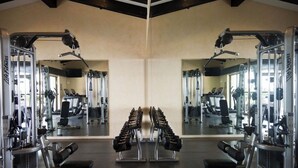 A gym with mirrored walls, weight machines, and benches. - Garza Blanca, 2 Bdr Panoramic View Hotel Suite in Puerto Vallarta with kitchen. (Jal.)