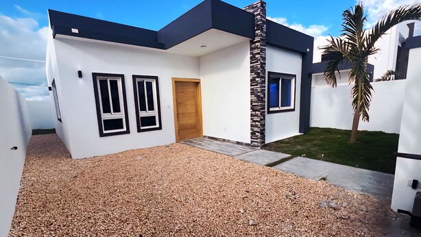 A modern two-story house with a white exterior, black trim, and a stone accent wall. - Charming 2-bedroom villa in lovely Punta Cana with AC, WiFi (Punta Cana)