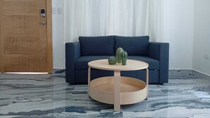 A room with a dark blue sofa, a round wooden coffee table with a lower shelf, and a marble-patterned floor. - Charming 2-bedroom villa in lovely Punta Cana with AC, WiFi (Punta Cana)