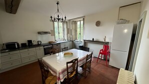 Una cocina compacta con una mesa de comedor, sillas, una araña y un refrigerador.