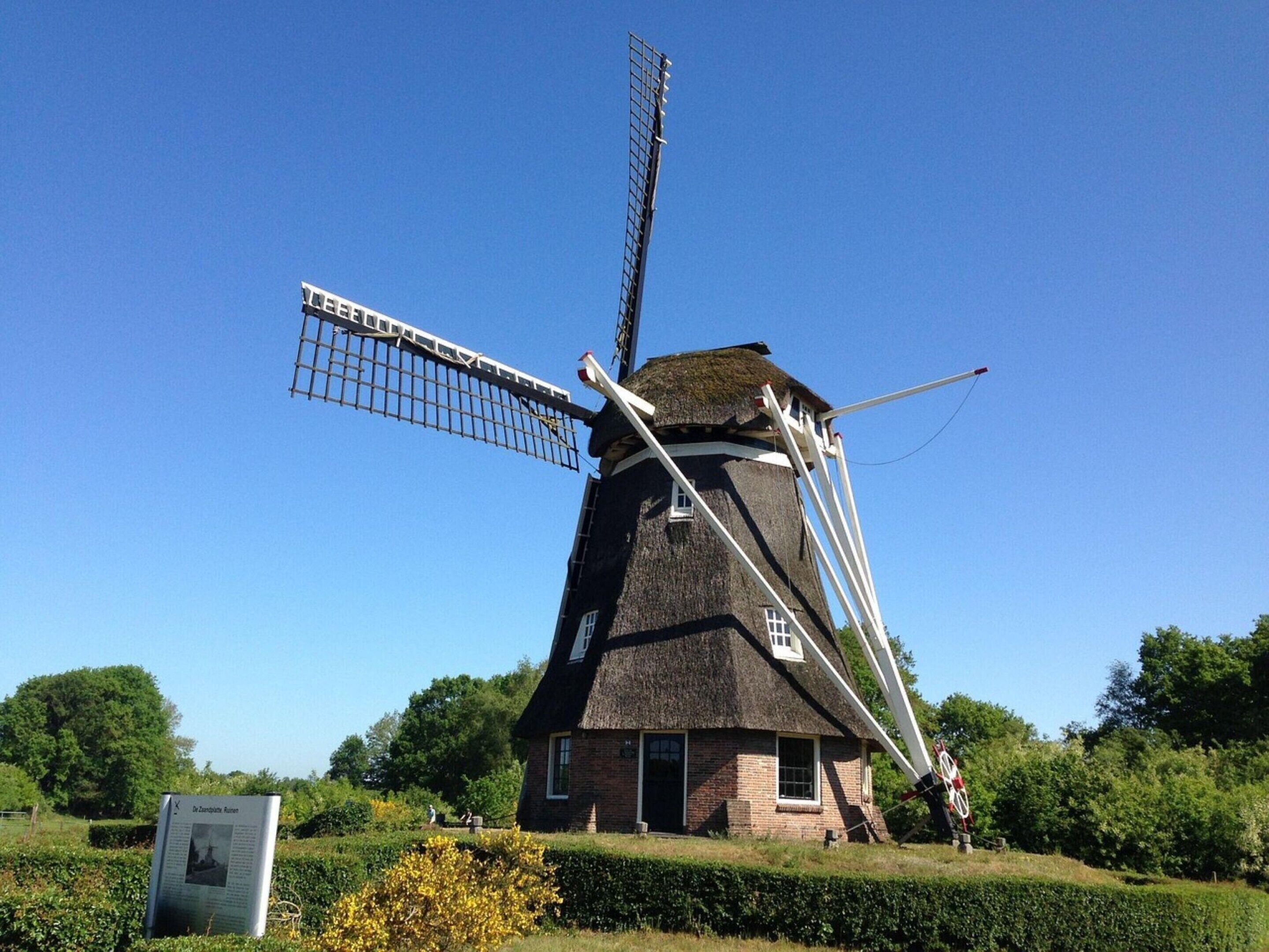 A traditional windmill with a thatched roof and a lattice structure.