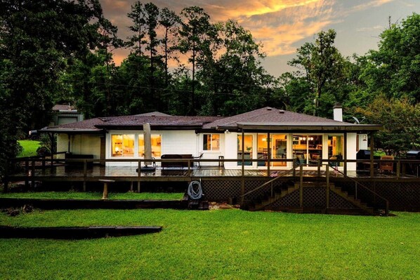 A two-story house with a covered deck, a visible staircase, and a lawn in front.
