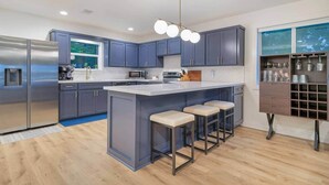 A modern kitchen with a central island, bar stools, stainless steel appliances, and a built-in wine rack. - Family Cove Retreat - newly remodeled! (Point Blank)