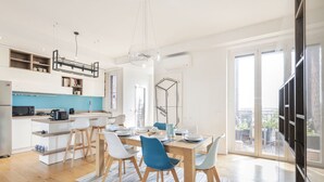Een moderne keuken met witte kasten, een blauwe achterwand en een eethoek met een houten tafel en blauwe stoelen.