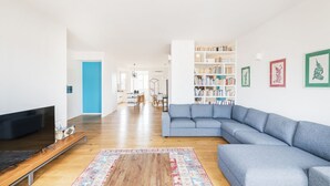 Een moderne woonkamer met een hoekbank, een flatscreen televisie, een houten salontafel en een vloerkleed met een patroon.