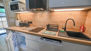 Een kleine keuken met een magnetron, broodrooster, waterkoker, spoelbak en vaatwasser.