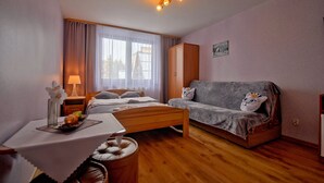 Ein gemütliches Zimmer mit Bett, einer Couch, einem kleinen Tisch mit einer Vase und einer Lampe.