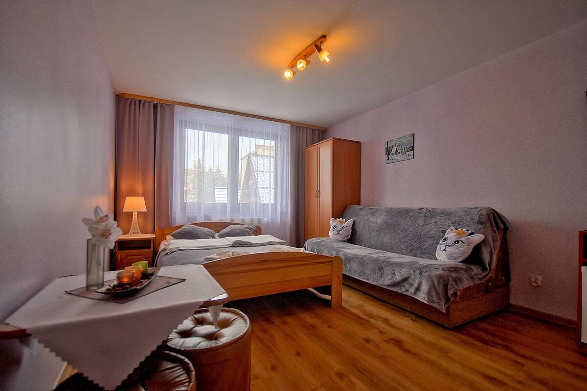 Une pièce confortable avec un lit, un canapé, une petite table ornée d’un vase et une lampe.