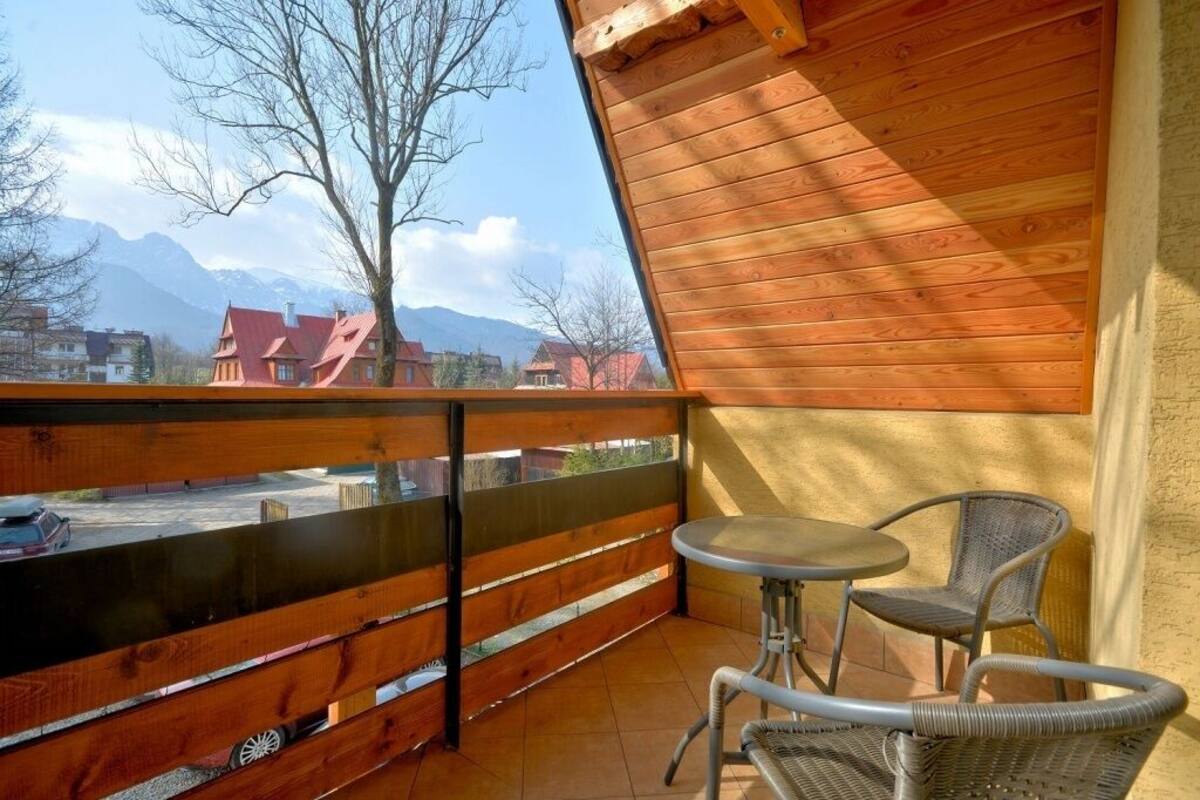 Un balcon doté d’une balustrade en bois, d’une table et de deux chaises en osier.