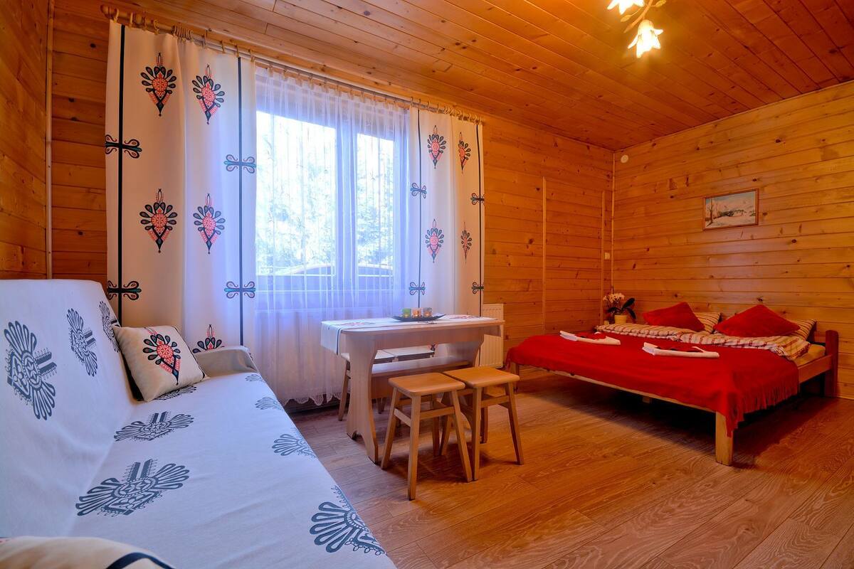 Une pièce chaleureuse, aménagée dans une cabane en bois, avec un lit, un bureau et une chaise.