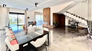 A modern interior with a dining area, a reception desk, and a staircase. - Villa de Luxe dans le Golf Argan resort - Comfort and Premium Services (Marrakech)
