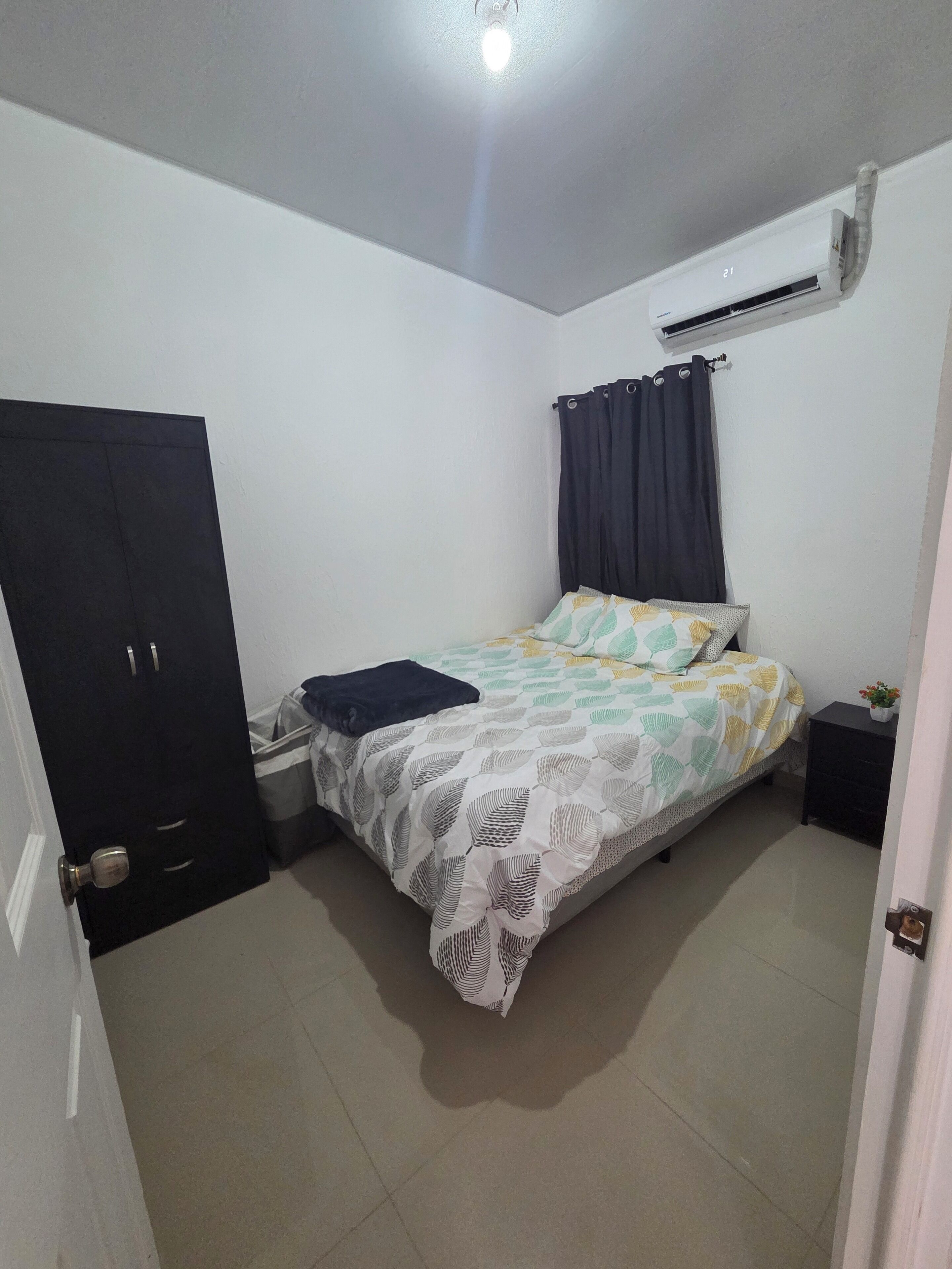 Ein Schlafzimmer mit Bett, Kleiderschrank, Klimaanlage und Nachttisch.
