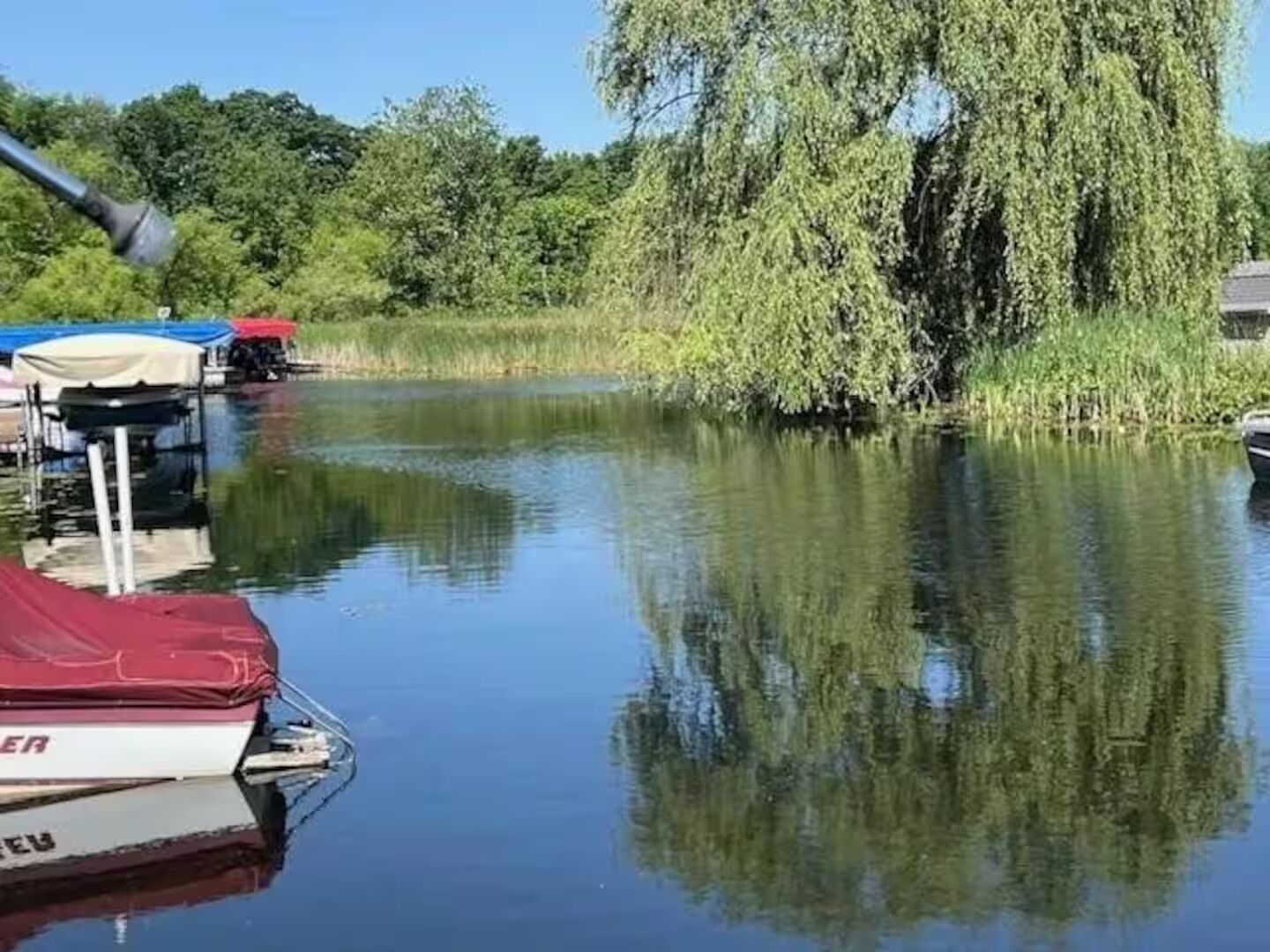 A calm river with a boat docked near the bank, surrounded by lush greenery and trees.