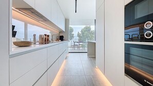 A modern kitchen with a long countertop, built-in appliances, and a view to the outdoors. - Monumental Sea Sky by Atlantic Holiday (Funchal)