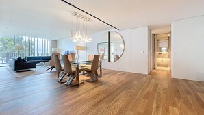A modern dining area with a glass table, wooden flooring, and a large mirror. - Monumental Sea Sky by Atlantic Holiday (Funchal)