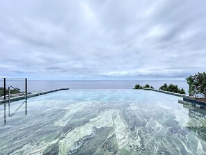 On peut clairement voir une piscine à fond de verre, entourée d’un petit muret et d’une clôture en métal.