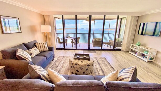 Un salón con sofá, mesa de centro y un balcón con vistas al mar.