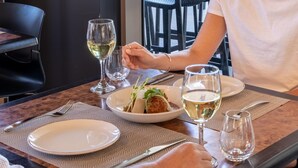 A dining table with a white plate, a bowl of food, and two glasses of white wine. - Best Western Cambridge Hotel Kununurra (Kununurra)