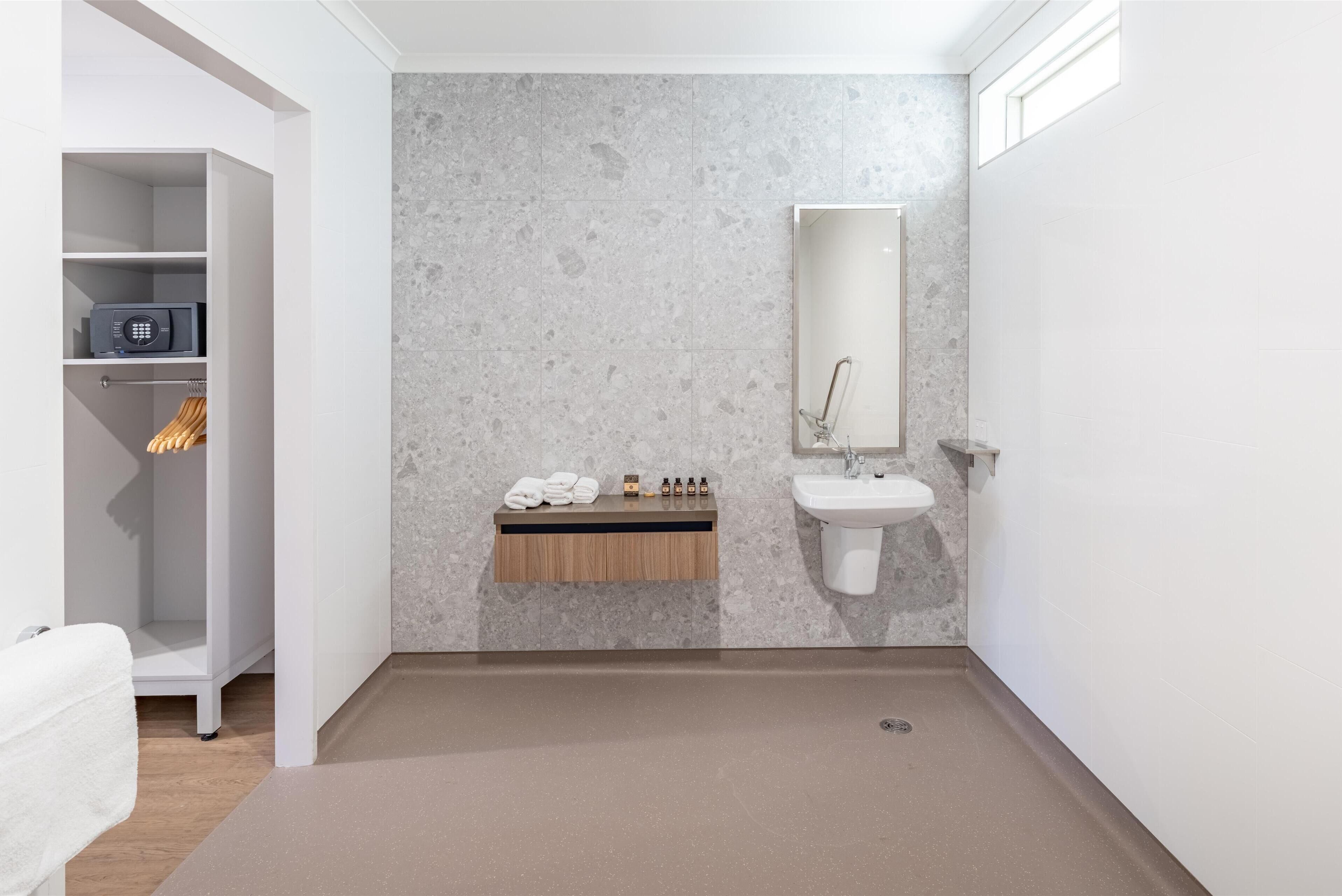 Une salle de bain moderne avec un mur en marbre, un meuble-lavabo en bois, un évier et un porte-serviettes.