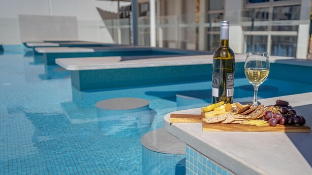 A poolside area with a table set with snacks and a bottle of wine. - Best Western Cambridge Hotel Kununurra (Kununurra)