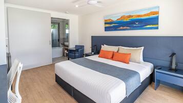 Quarto de hotel moderno com uma cama grande, uma escrivaninha, uma cadeira e um quadro na parede.