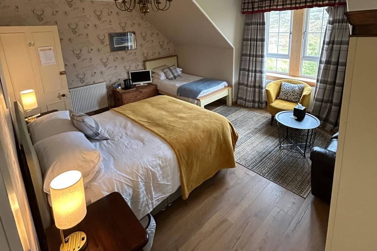 Une chambre à coucher comprenant un lit, une table de chevet, une lampe et un petit bureau avec une chaise.