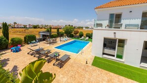 Una casa moderna con piscina, mobiliario exterior y un césped bien cuidado.