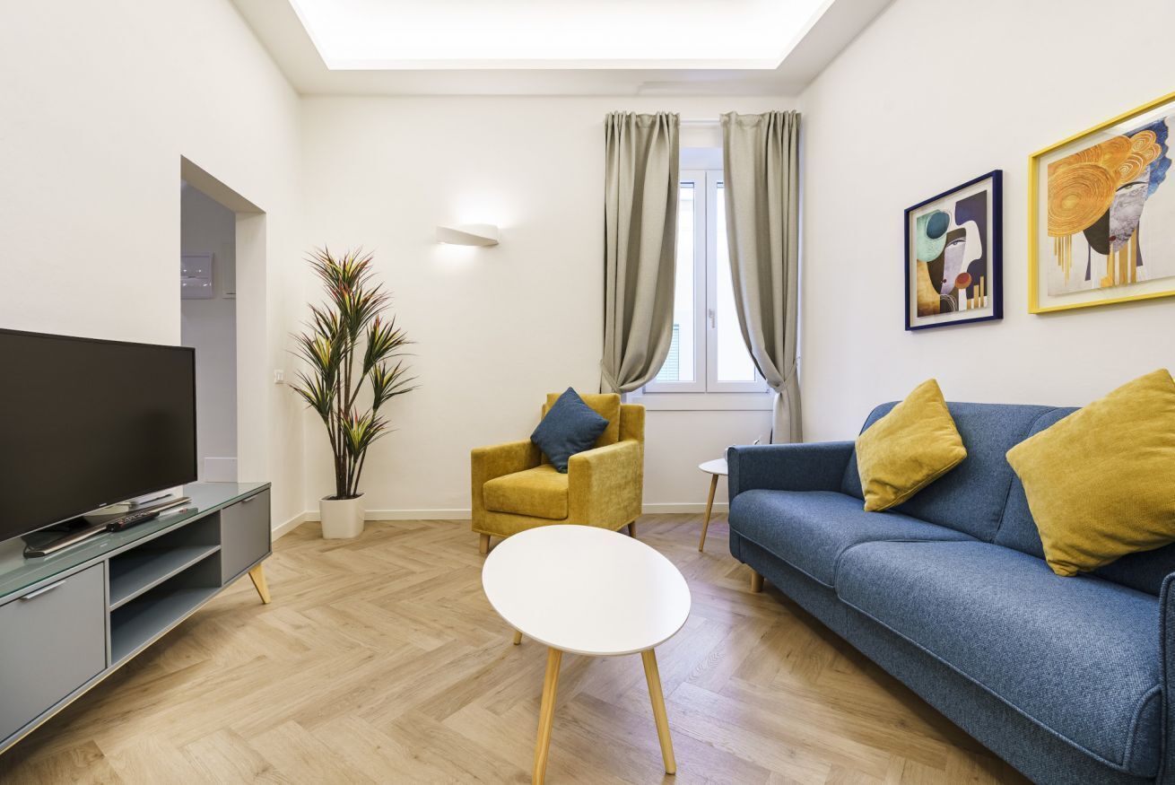 Un salon moderne avec un téléviseur à écran plat, un canapé, un fauteuil et une petite table.