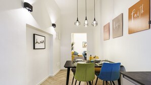 A modern dining area with a black table, two chairs, and a hanging light fixture. - Designer Apartment in Oltrarno (Firenze)