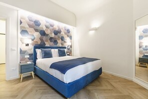 Ein modernes Schlafzimmer mit einem Kopfteil im geometrischen Muster, einem Bett mit blauer Bettwäsche, einem Nachttisch und einem Spiegel.