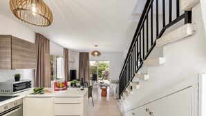 Cozinha moderna com armários brancos, uma ilha central e uma área de jantar com mesa e cadeiras.