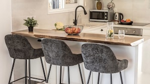 Una cocina con una isla central, taburetes de bar, un lavamanos y un microondas.
