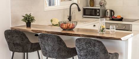 A kitchen with a central island, bar stools, a sink, and a microwave.