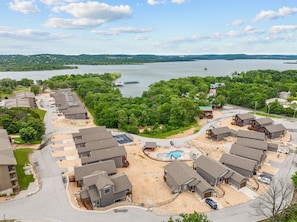 Un quartier résidentiel avec des maisons, une piscine et un lac en arrière-plan.