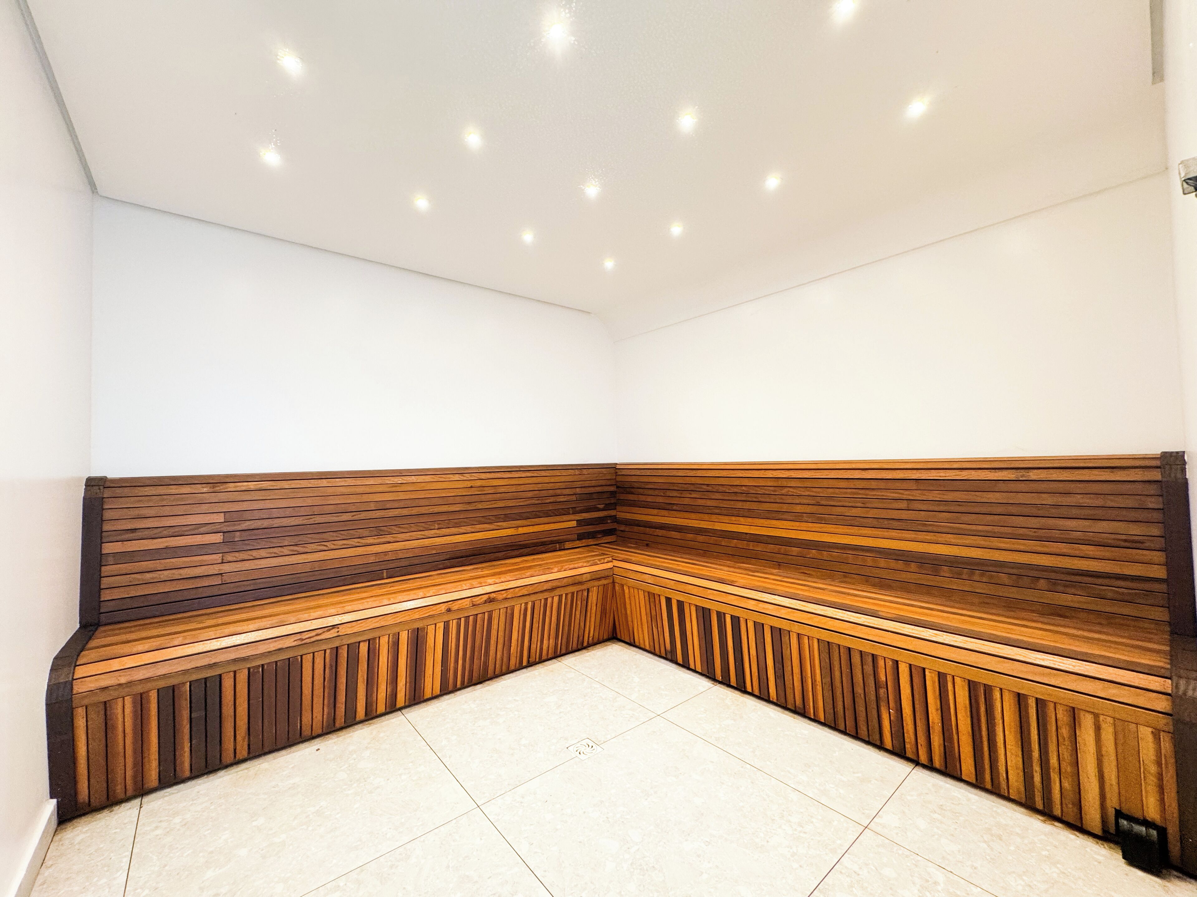 A corner seating area with a wooden bench and a tiled floor.