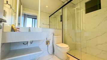 Een moderne badkamer met een douchecabine van glas, een wit toilet en een vloer van marmer.