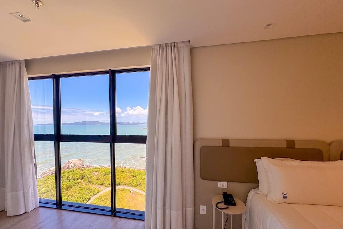 Habitación de hotel con un ventanal que ofrece vistas a un paisaje costero.