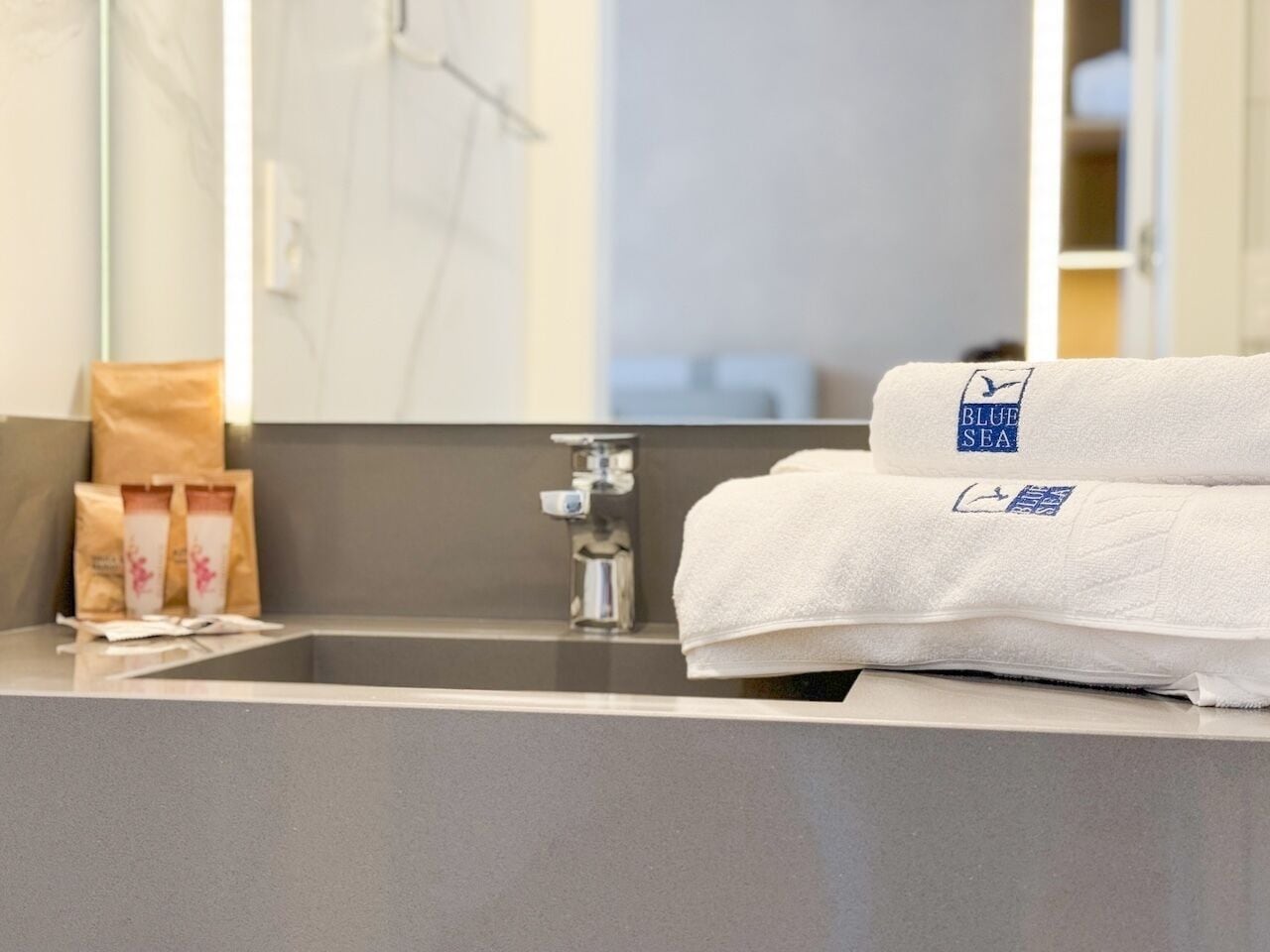 A bathroom with a modern sink, a towel, and a bag of toiletries.