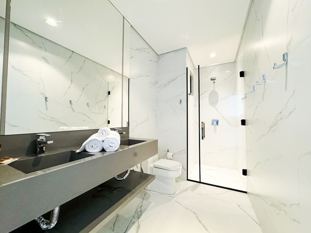 Un baño moderno con tocador de mármol, cabina de ducha de vidrio y retrete.