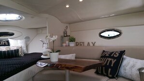 A cozy interior with a cushioned seating area, a small table with a plant, and decorative pillows. - Bob's Yer Uncle in Port Dalhousie (St. Catharines)