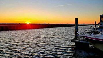 Ein Sonnenuntergang über ruhigem Wasser mit einem Steg und einem Boot.
