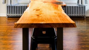A room with a long wooden table, two windows with curtains, an air conditioning unit, a radiator, and a hanging light fixture. - Stylishly Remodeled Queen Victoria Loft (Niagara Falls)