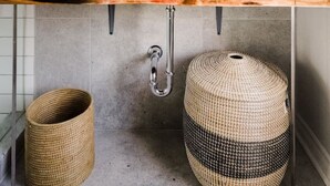 A bathroom with a large mirror, a blue bowl sink, a wooden countertop, and two woven baskets. - Stylishly Remodeled Queen Victoria Loft (Niagara Falls)