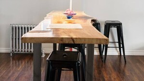 Une cuisine moderne avec une table en bois, des tabourets noirs et un luminaire suspendu.