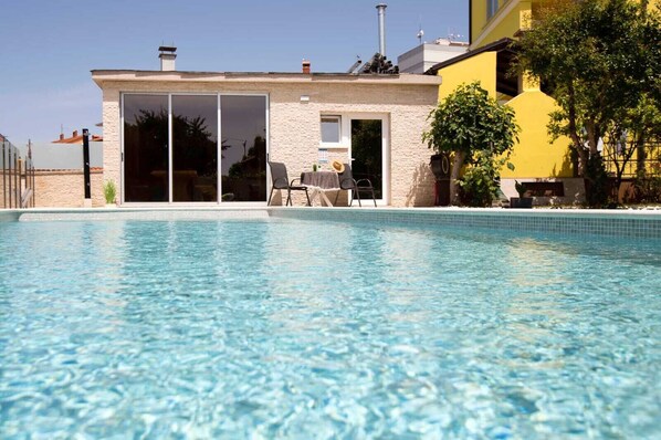 A clear swimming pool with a house in the background.