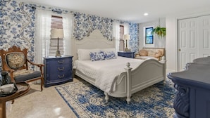A bedroom with a bed, dresser, chair, and a window with blinds.