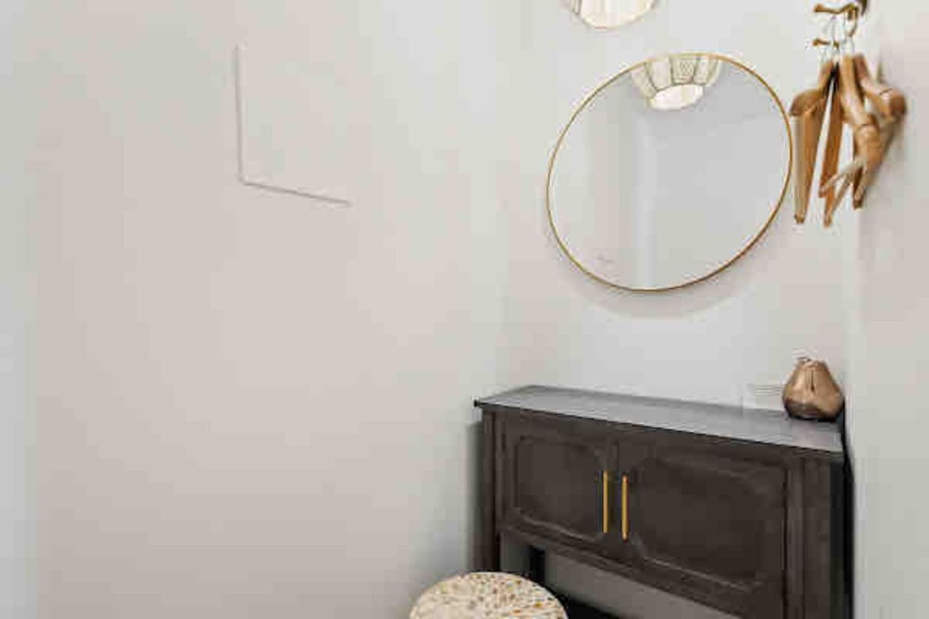 A bathroom with a dark wooden vanity, a round mirror, and a towel rack.