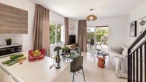 A modern kitchen with a dining area, a TV, and a staircase. - Larnaca Seaside Villa Marina 43 (Pervolia)